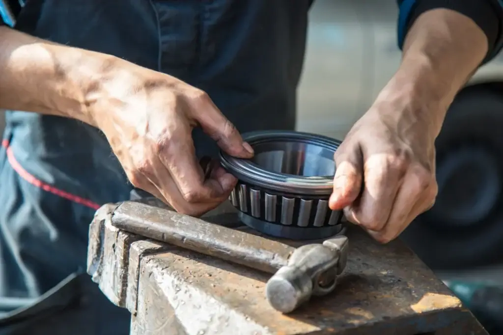 Auto mechanic makes the maintenance of the bearing of the cargo trailer